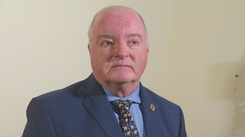 A man in a suit sitting next to a blood pressure machine