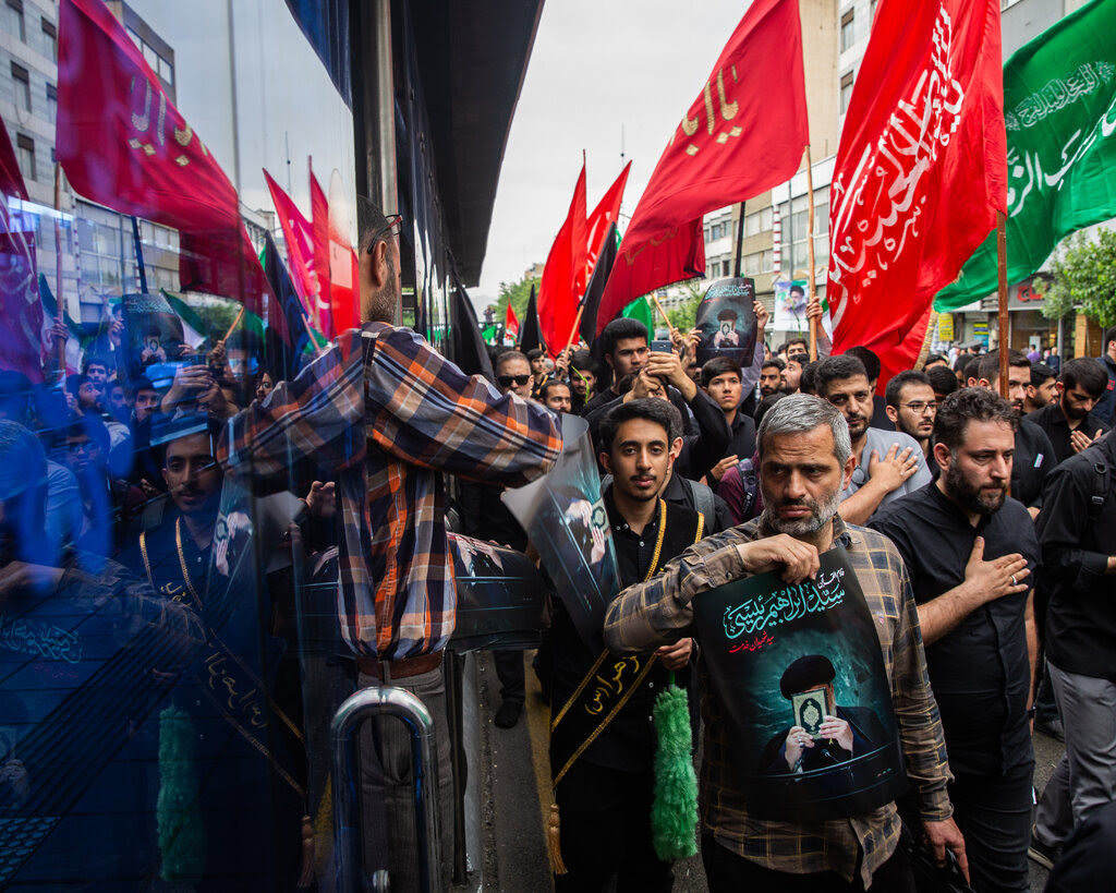 People carrying red and green flags gathered in Tehran to mourn the loss of the president. 