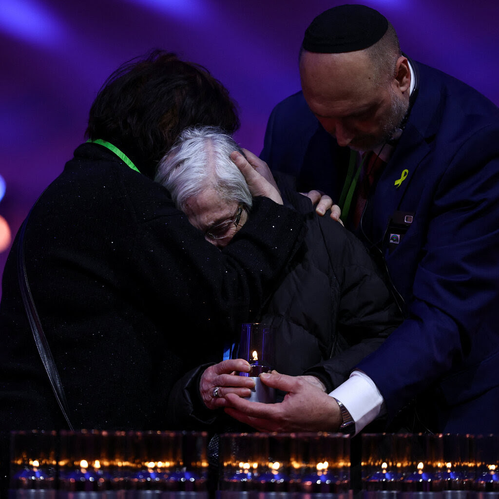 A Holocaust survivor is comforted as she places a candle during the commemoration ceremony for the liberation of Auschwitz.