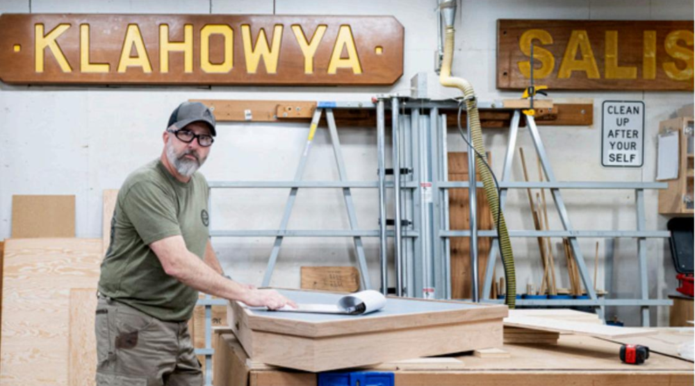 Person standing at a table working in a sign shop