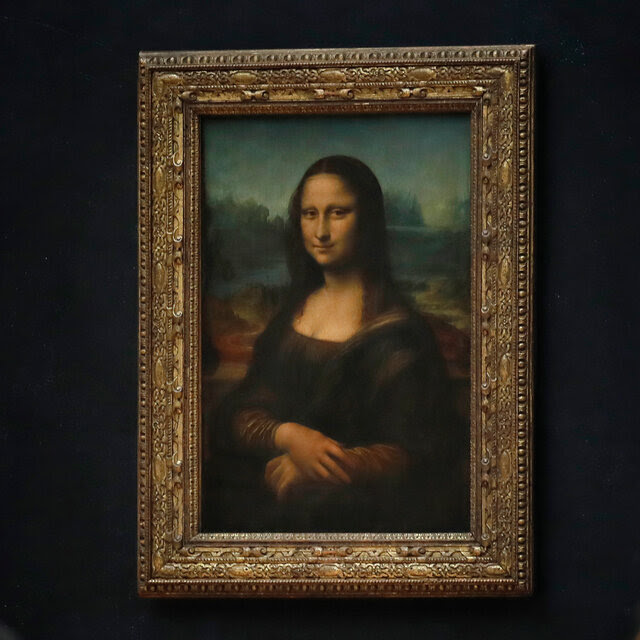 The Mona Lisa displayed on a wall as two people wearing masks walk past it. 