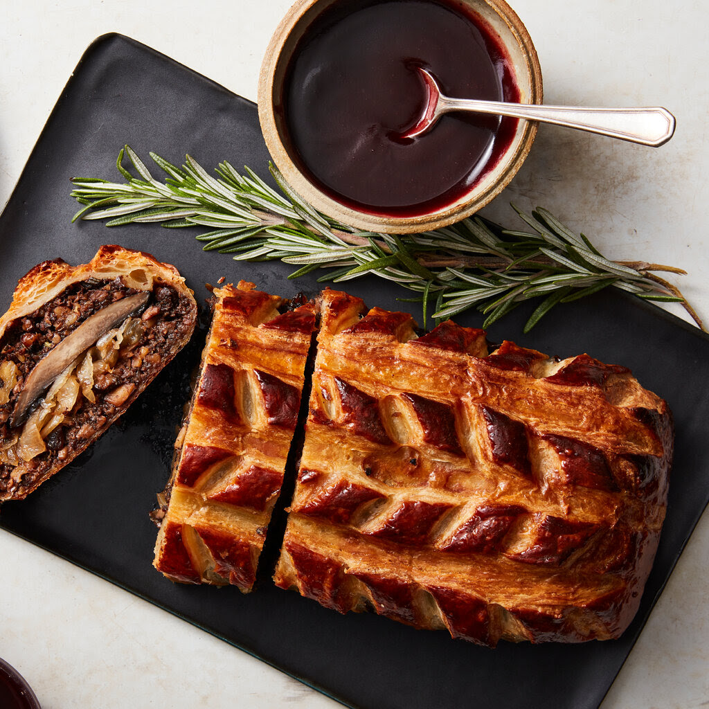 A sliced pastry seen from above. One slice is on its side, showing a rich filling of finely chopped mushrooms.