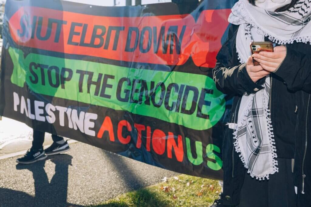 Palestine Action protesters hold up a sign saying 'shut Elbit down, stop the Genocide' in a demonstrations in front of Elbit Systems in New Hampshire (Photo: Maen Hammad)