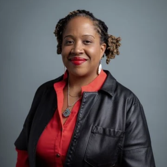 Smiling WOC with a red shirt, black jacket and red lipstick