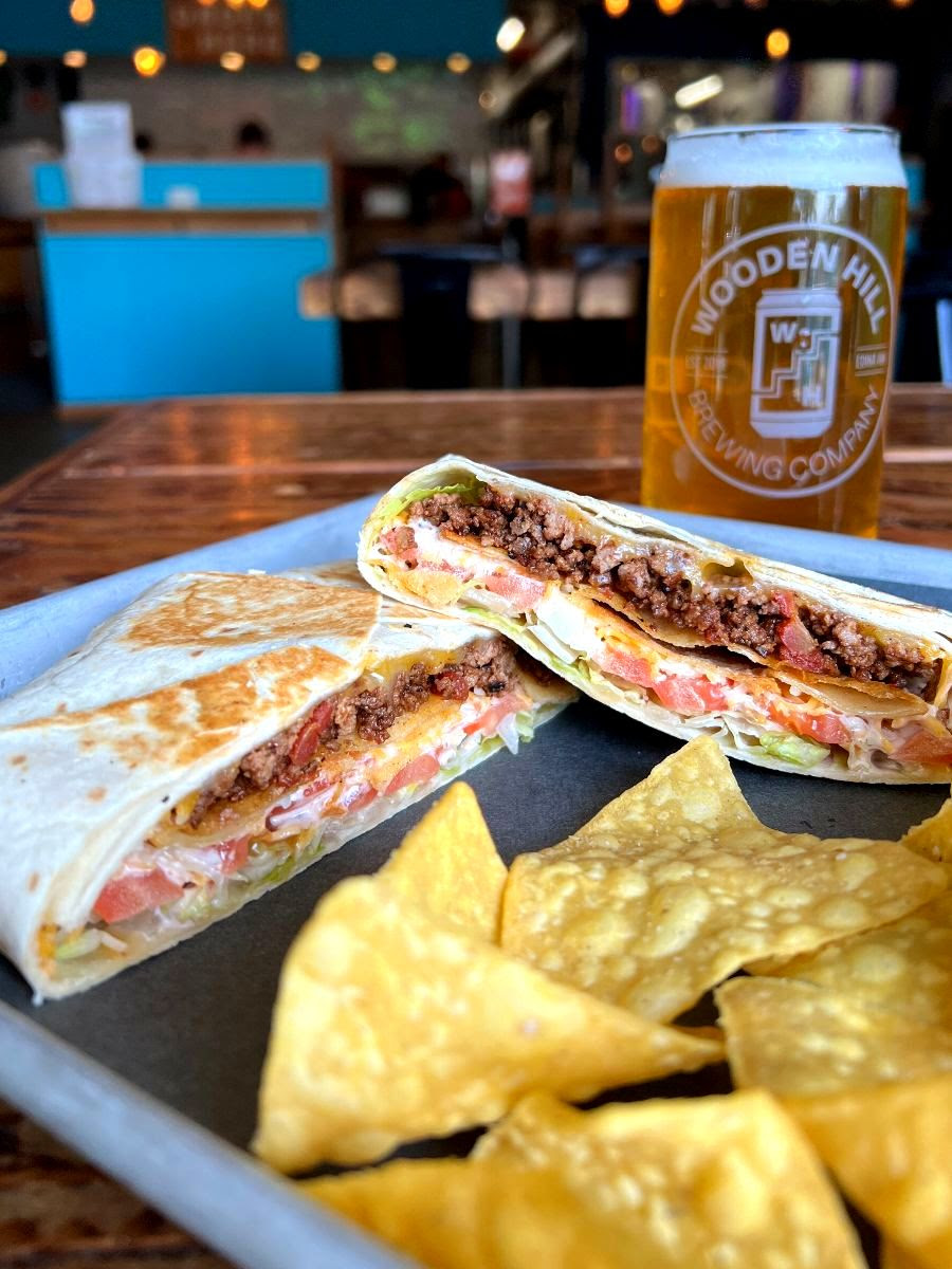A picture of sliced crunchy wrap with nachos and a drink on the side.