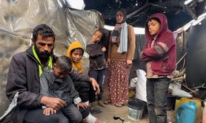 La familia Mahmoud Al-Daqs preparando comida en su deteriorada tienda de campaña.  .