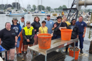 A group of people post on a dock standing behind a table with two orange baskets