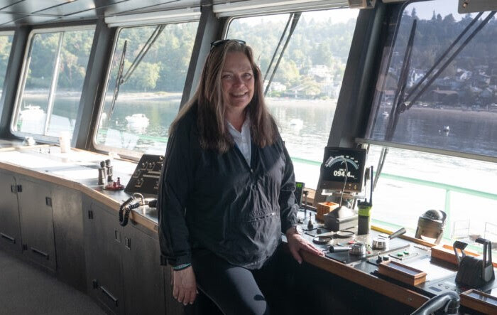 Person standing in the wheelhouse of a ferry