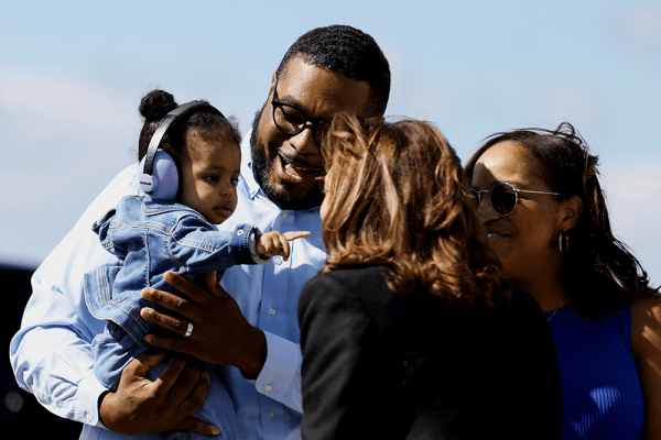 Father holds baby daughter, who is pointing at Vice President Kamala Harris.