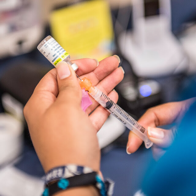 A certified medical assistant fills a needle with the drug Gardasil, used for HPV vaccinations.