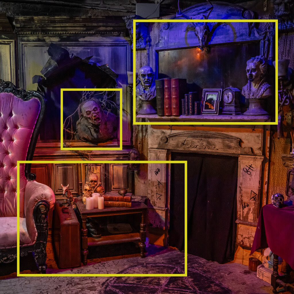 A room in a haunted house with scary busts above a fireplace and skulls on a side table. 