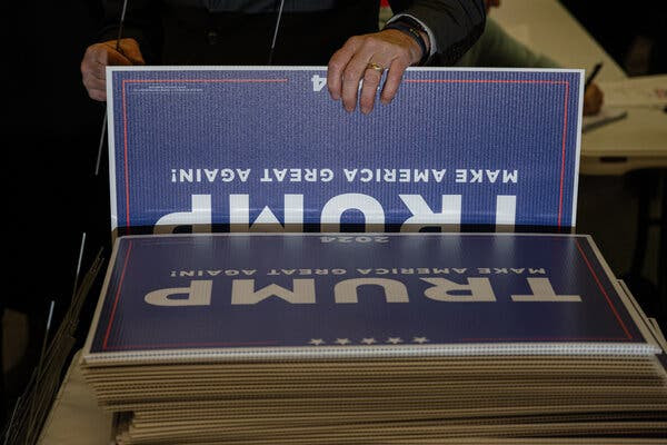 A stack of blue signs reading “Trump Make America Great Again!”