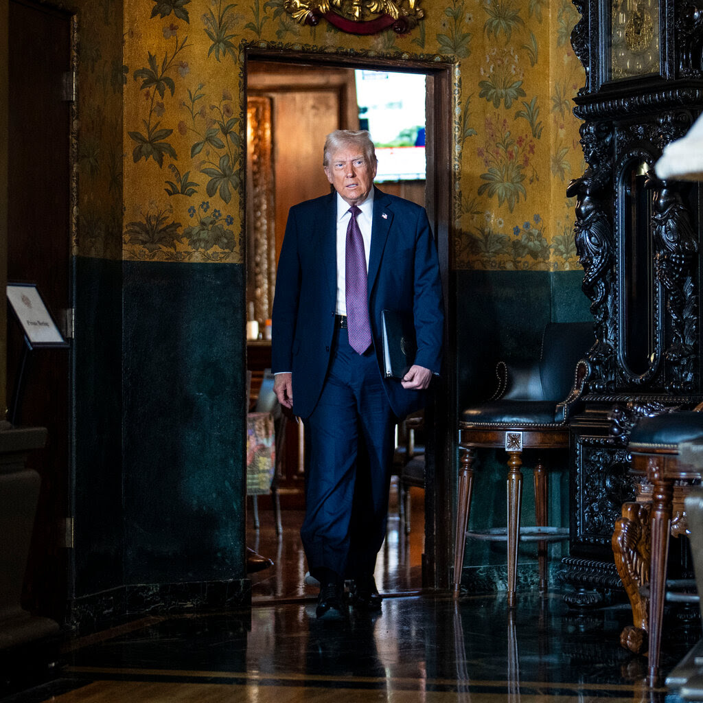 President-elect Donald Trump walking through an ornate room. The walls are covered in gold wallpaper and a large grandfather clock sits near a corner.