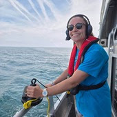 Person on a boat holding scientific equipment