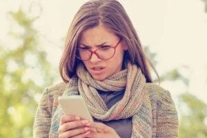 woman looks angrily at phone