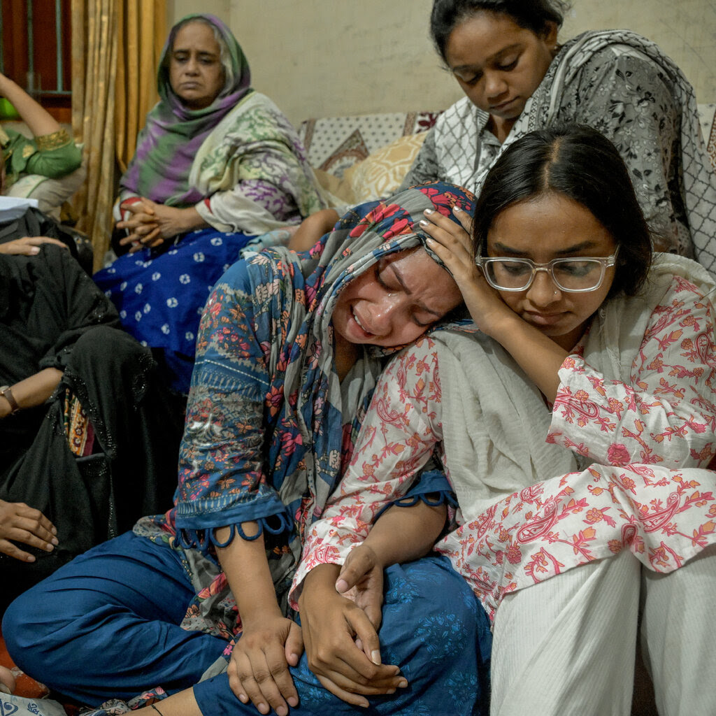 Many Bangladeshi women sit near each other, mourning or looking sad.