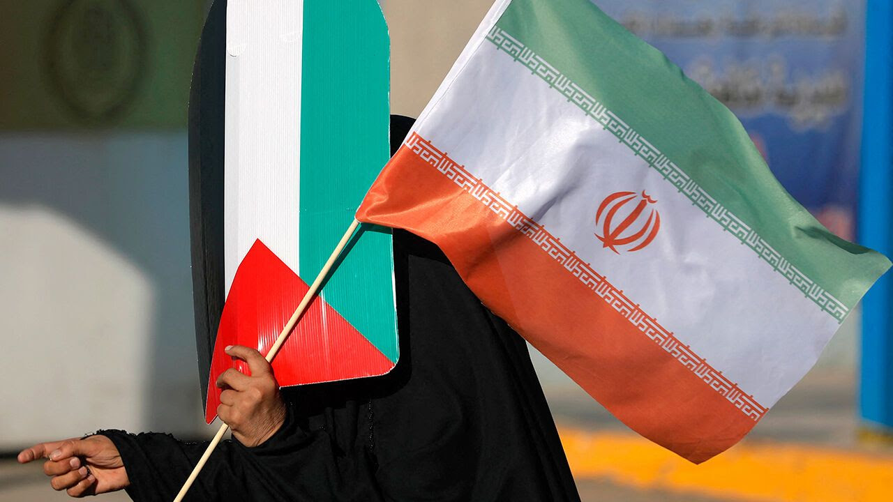 An Iraqi woman carries the flags of Iran and Palestine during a march in the Kadhimiya district of Baghdad