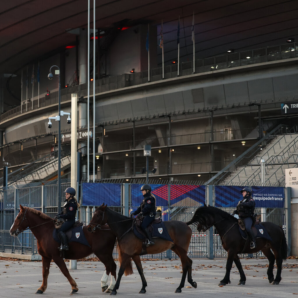 Police officers on horseback outside a stadium.