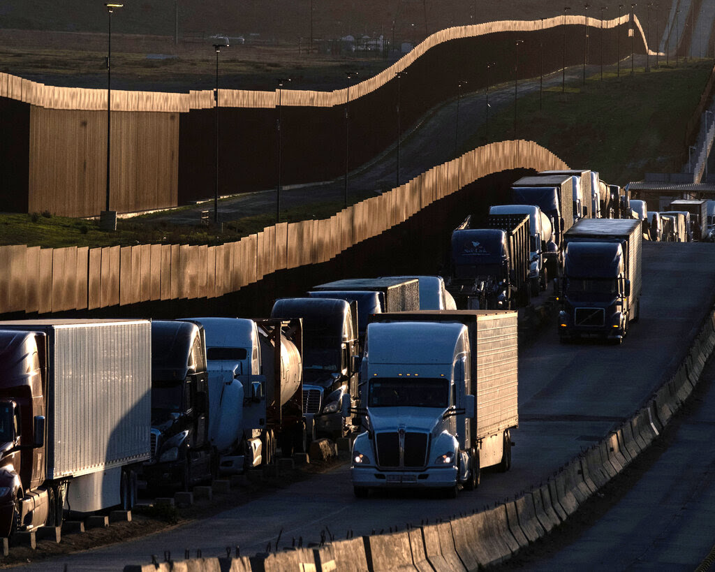 A row of trucks along a border fence.