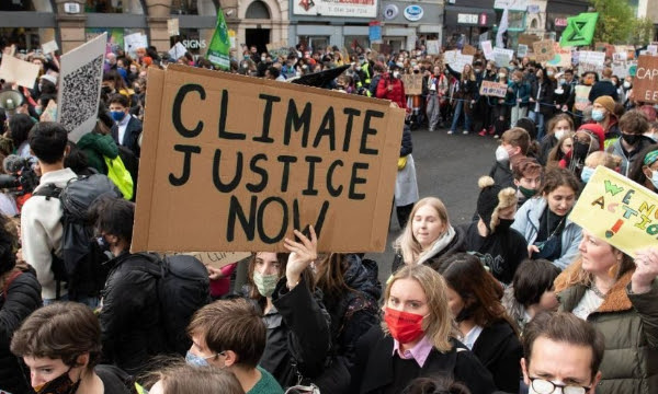 Cardboard Climate Justice Now placard held high by protester in crowd