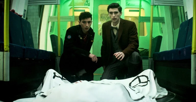 (L to R) Jayden Revri as Charles Rowland and George Rexstrew as Edwin Payne looking at a body covered by a white sheet inside of a train