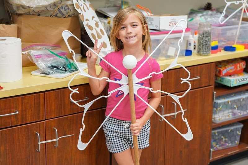 girl posing with her butterfly creation made out of recycled materials