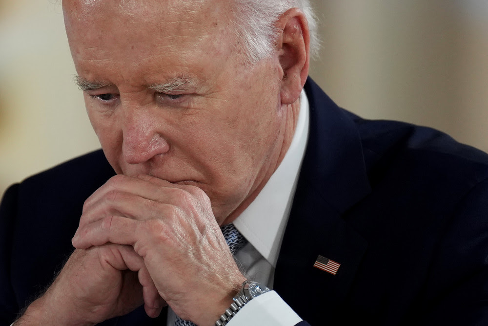 Joe Biden leans his head on his clasped hands.