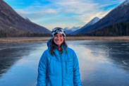 Emily Mailman stands in front of lake and mountains