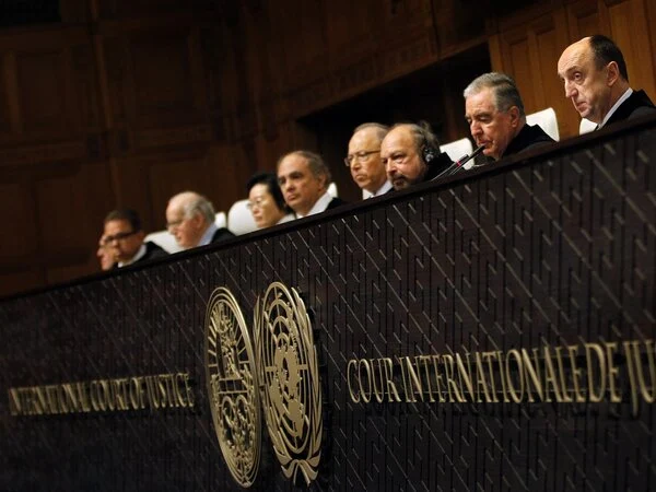 A row of judges sits at a table with the words ‘The International Court of Justice’ emblazoned on it.