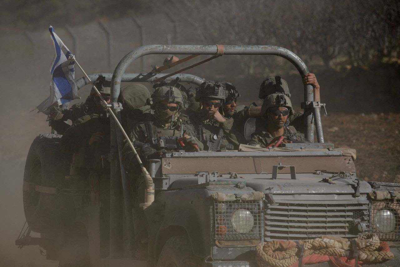 An Israeli military vehicle rides on the Golan Heights side of the ceasefire line with Syria on Dec. 18. (Shir Torem/Reuters)