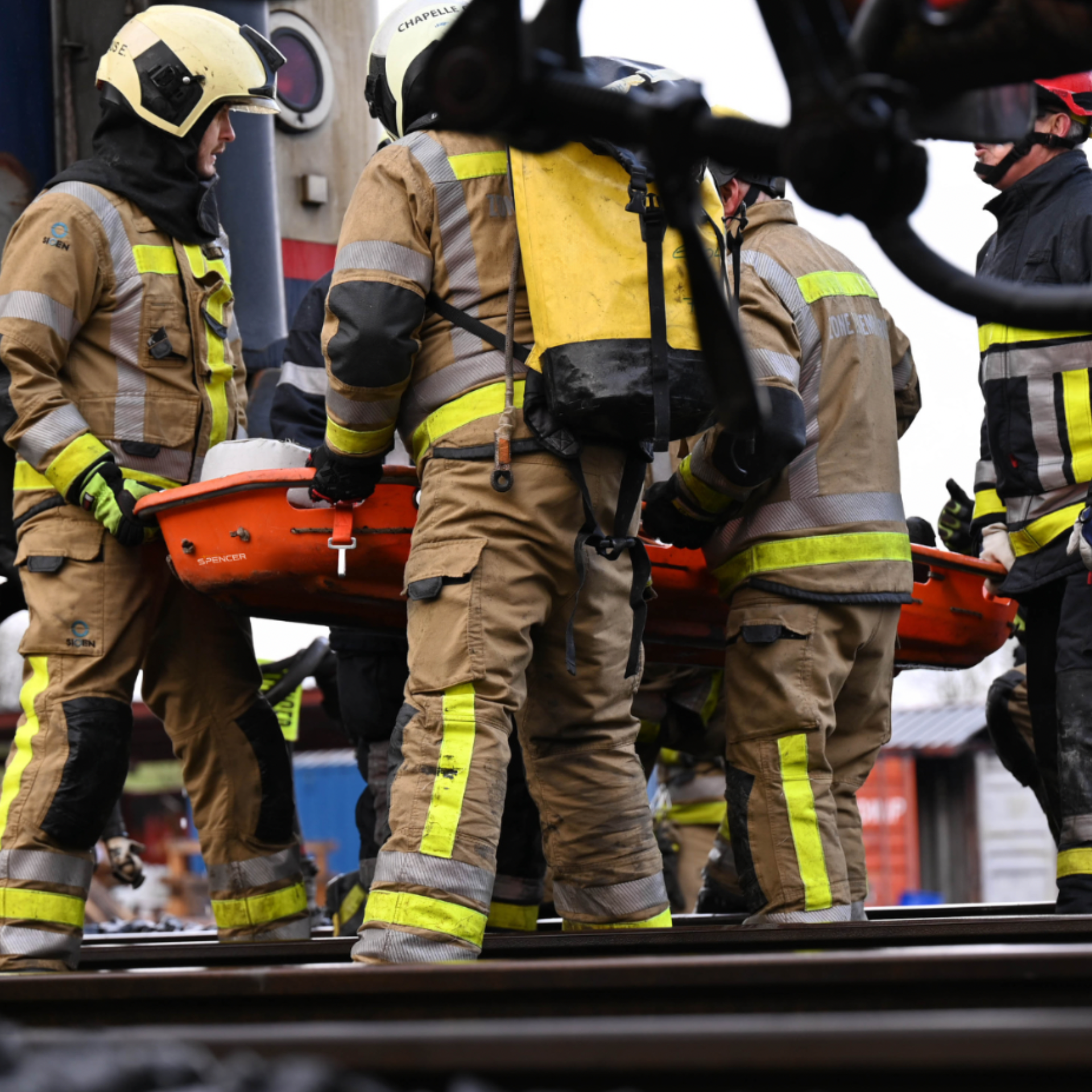 Firefighters carrying a basket stretcher with a casualty