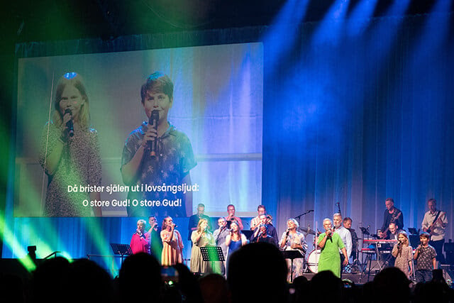 Siblings Agnes and Alfred Quint (on screen) join with singers from the Uniting Church in Sweden to lead worshippers in “O Store Gud,” the original Swedish name of the hymn English speakers know as “How Great Thou Art,” during the World Methodist Conference in Gothenburg, Sweden. Photo by Klaus Ulrich Ruof, Germany Central Conference.