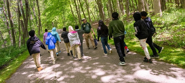 A DNR park interpreter leads a group of about a dozen kids on a nature hike through Maybury State Park