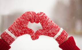 Person wearing red mittens holding a small snowman