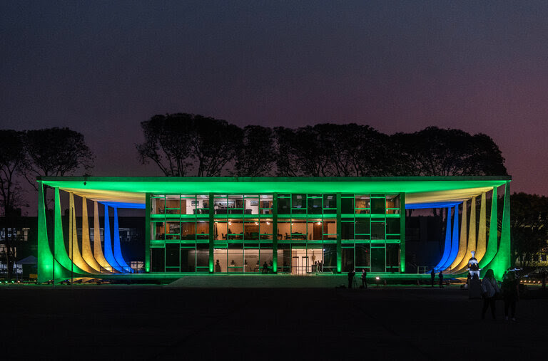 A view of a building lit up in blue, yellow and green.