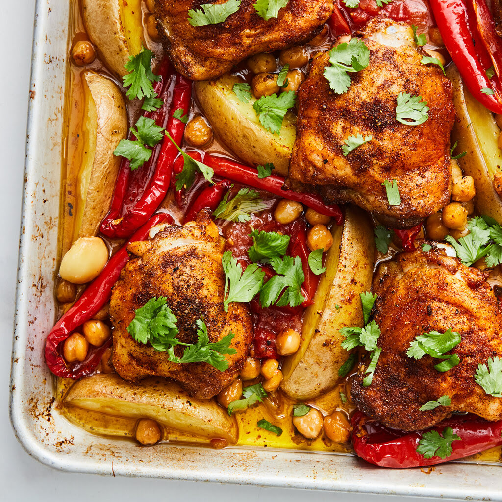 A chicken and chickpea tray bake with shiny red peppers and green cilantro.