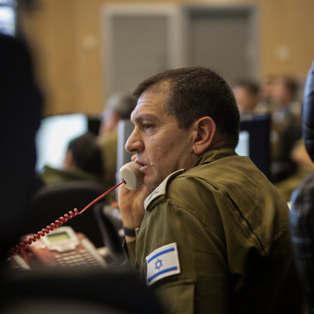 An Israeli officer in uniform talks on a landline telephone.