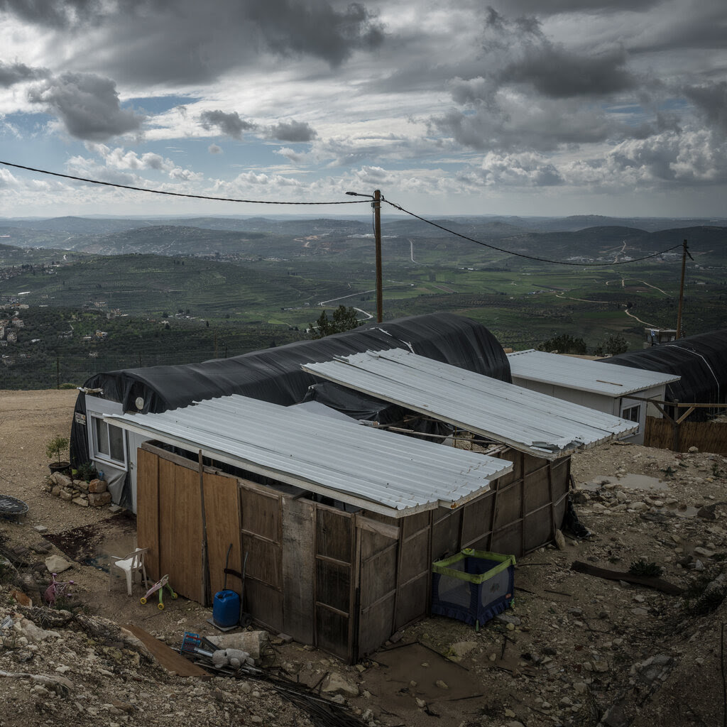 A set of makeshift cabins on a dirt road overlooking rolling hills.