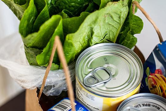 Lettuce, pasta, and canned goods in a brown paper bag