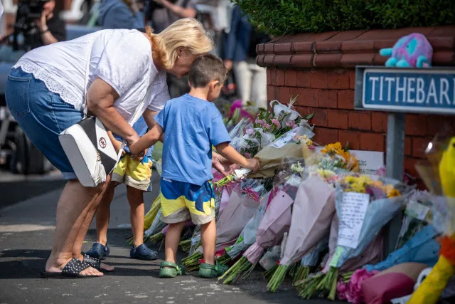 People lay flowers near the scene in Hart Street, Southport, where three children died and eight were injured in a 