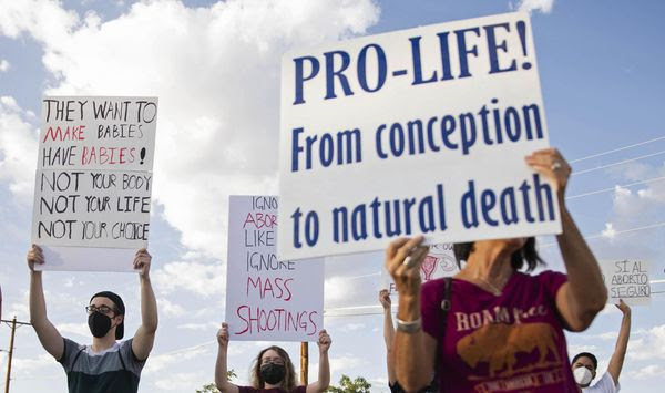 An anti-abortion advocate along with abortion rights advocates hold up signs during the Emergency Pro-Life Rally for New Mexico in Las Cruces, N.M., on Tuesday, July 19, 2022. New Mexico&#x27;s governor has signed a new executive order that pledges $10 million to build a clinic that would provide abortions and other pregnancy care. Democrat Michelle Lujan Grisham said Wednesday, Aug. 31, 2022, that &amp;quot;the goal here is build it and they will come.&amp;quot; She said New Mexico already has seen an influx of patients following the U.S. Supreme Court&#x27;s decision in June to overturn Roe vs. Wade as abortions have ceased in other states. (Meg Potter/The Las Cruces Sun News via AP, File)