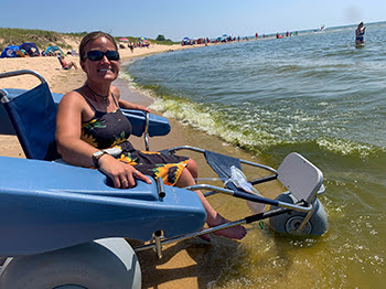 A woman dips her feet into Lake Michigan on a sunny day.