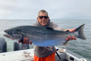 Oregon angler Jim Anderson holds up a wild Oregon Coast coho salmon that he caught aboard a boat.