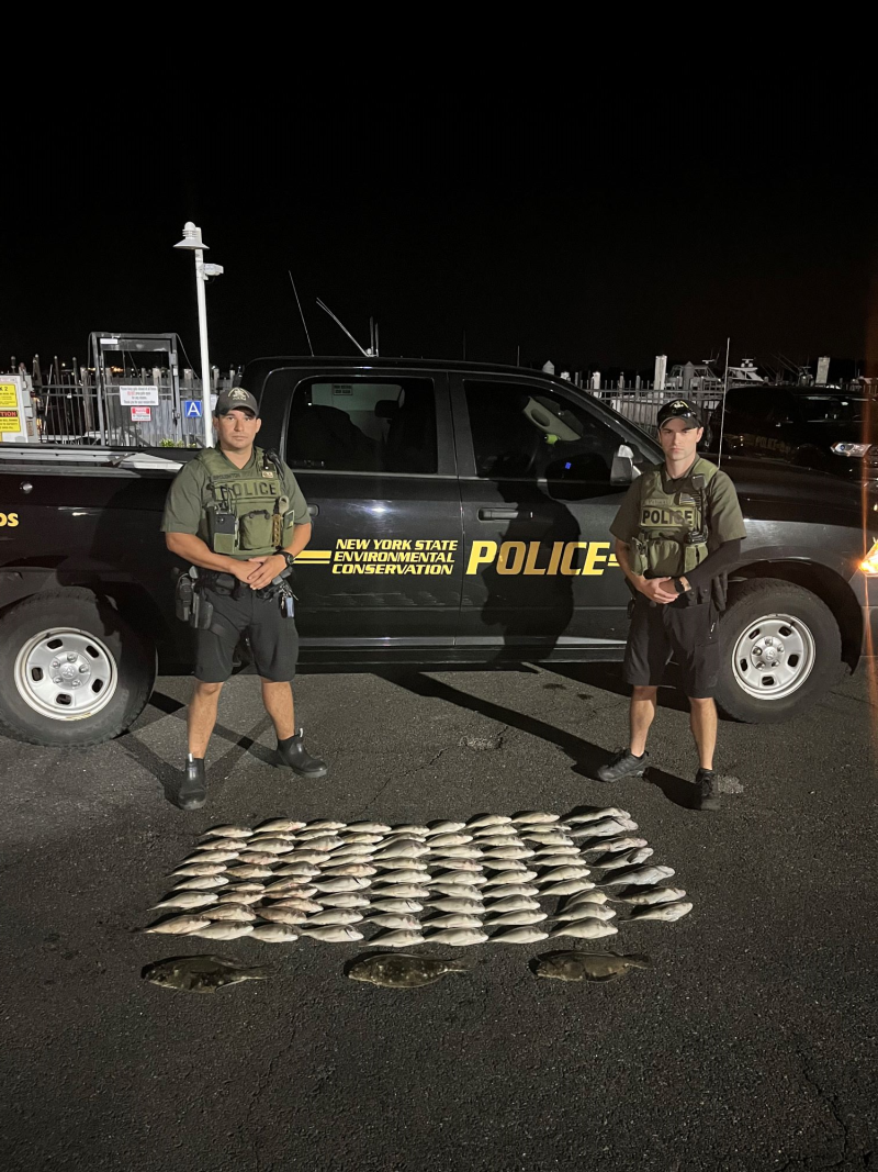 Two ECOs stand near seized fish that lay on the ground