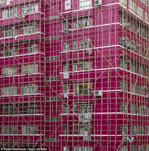 Old school: Construction workers in Hong Kong still use traditional bamboo to build scaffolding covering 21st century buildings