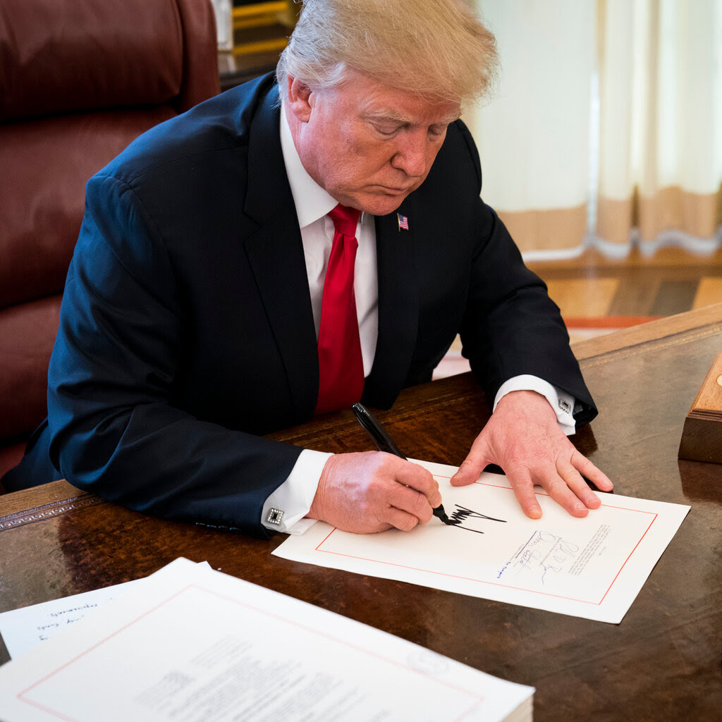 Donald Trump signing a piece of paper. 