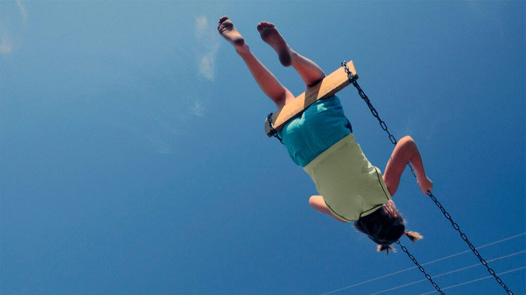 Child swinging on a swing against a blue sky