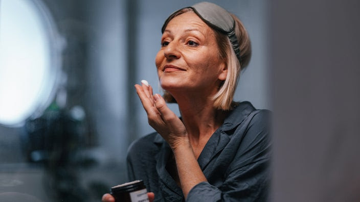 Older woman applying face cream.