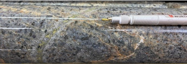 b) P106, 168m depth. Quartz-chalcopyrite D-type with sericite selvage cutting rejuvenated A-veins with K-feldspar in granodiorite