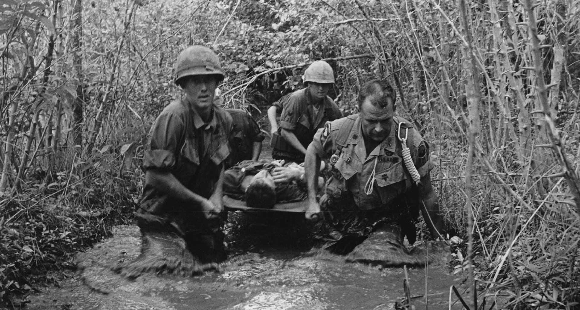 U.S. soldiers carry a wounded comrade through a swamp. National Archives photo